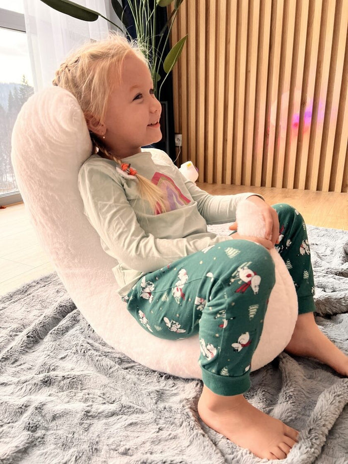 Child relaxing against soft white moon pillow, showing supportive design for toddlers