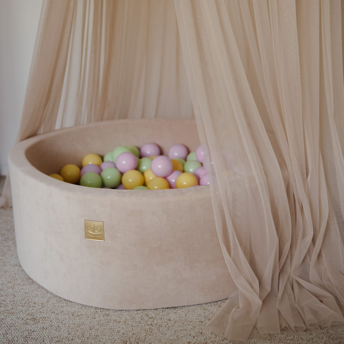 Close-up of beige ball pit with spring pastel foam balls and sheer canopy