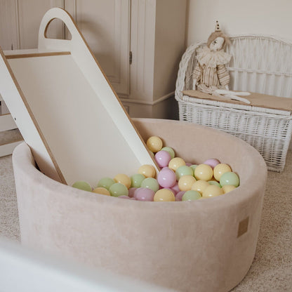 Beige ball pit with slide attachment and multicolored balls for toddler play